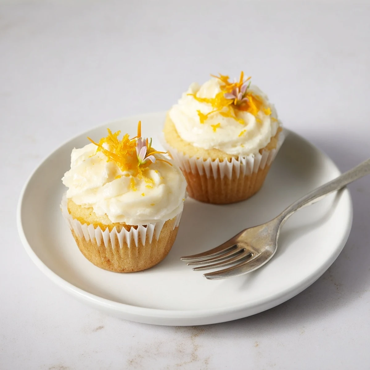 Fluffy orange blossom cupcakes topped with creamy citrus frosting and garnished with fresh orange zest
