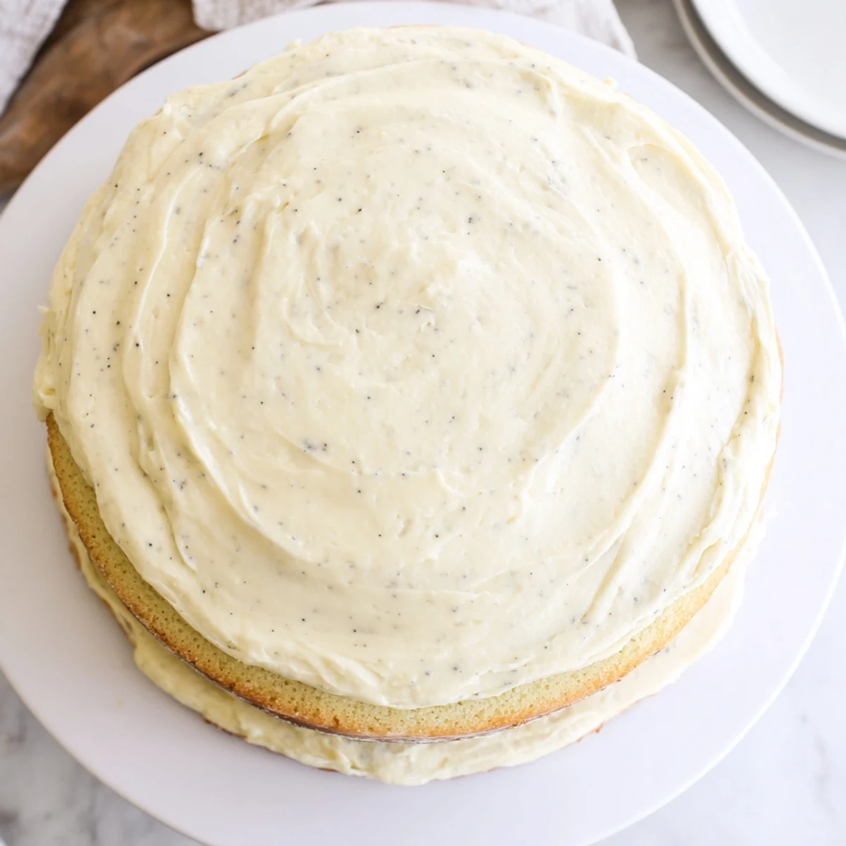 Two round vanilla bean birthday cake layers stacked high with creamy white buttercream frosting