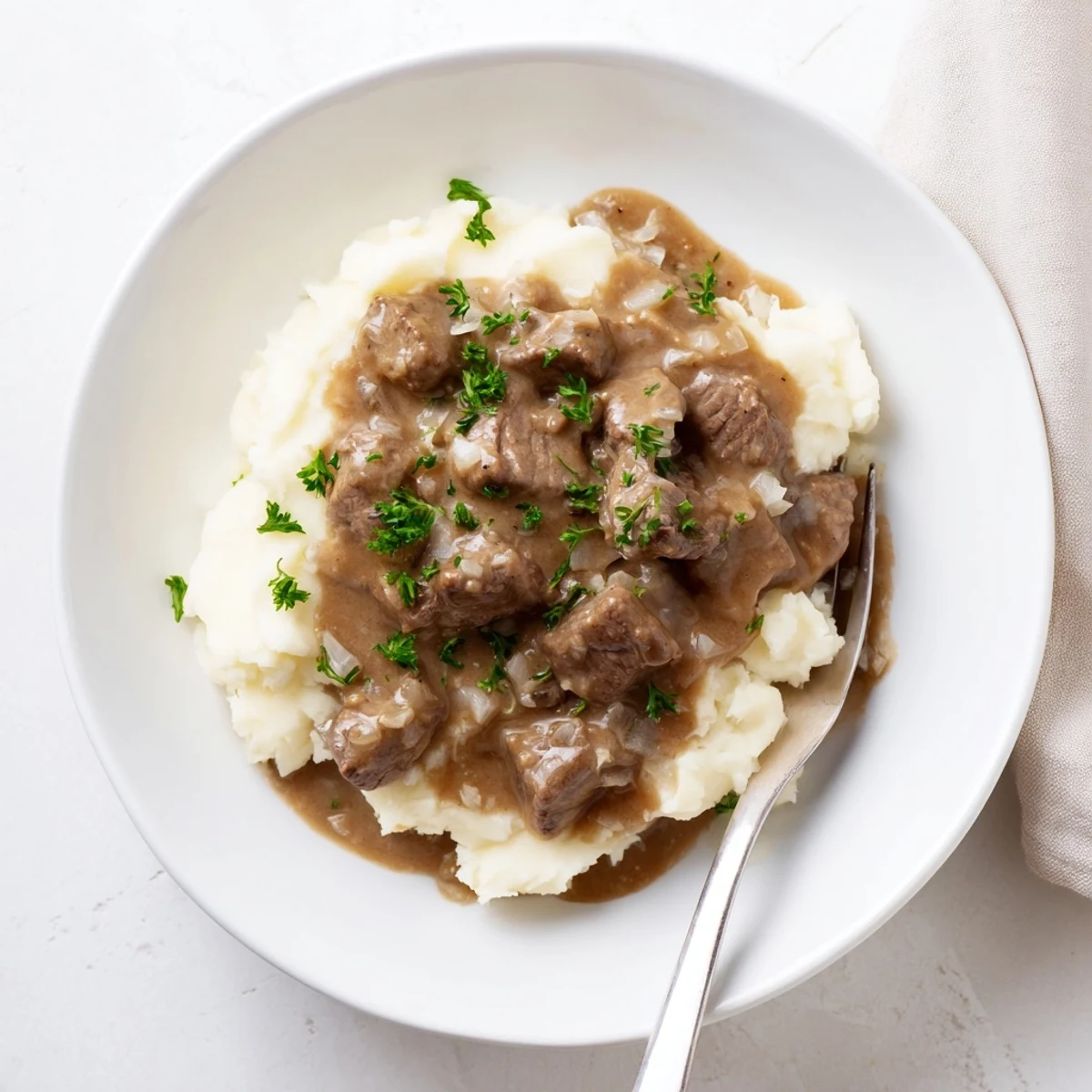 Tender slow cooker beef tips swimming in rich brown gravy over creamy mashed potatoes