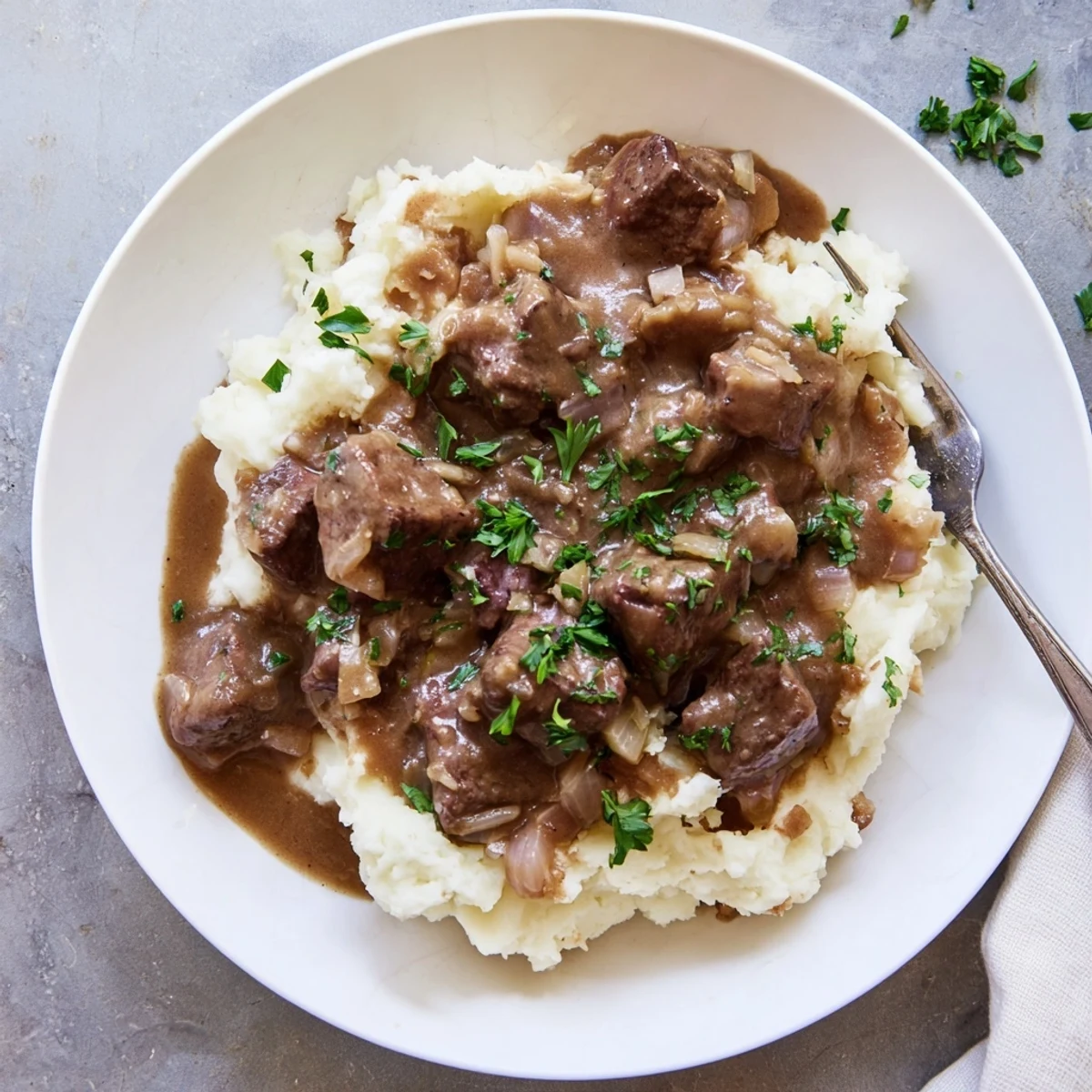 Heaping bowl of slow cooker beef tips and gravy served alongside fluffy buttered noodles