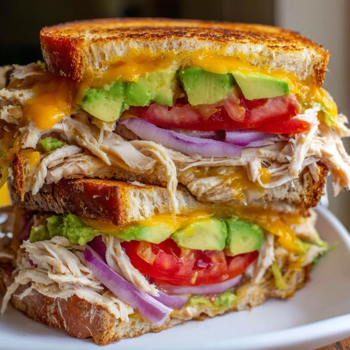 Toasted sourdough chicken avocado melt sandwich layered with creamy avocado and melted cheddar