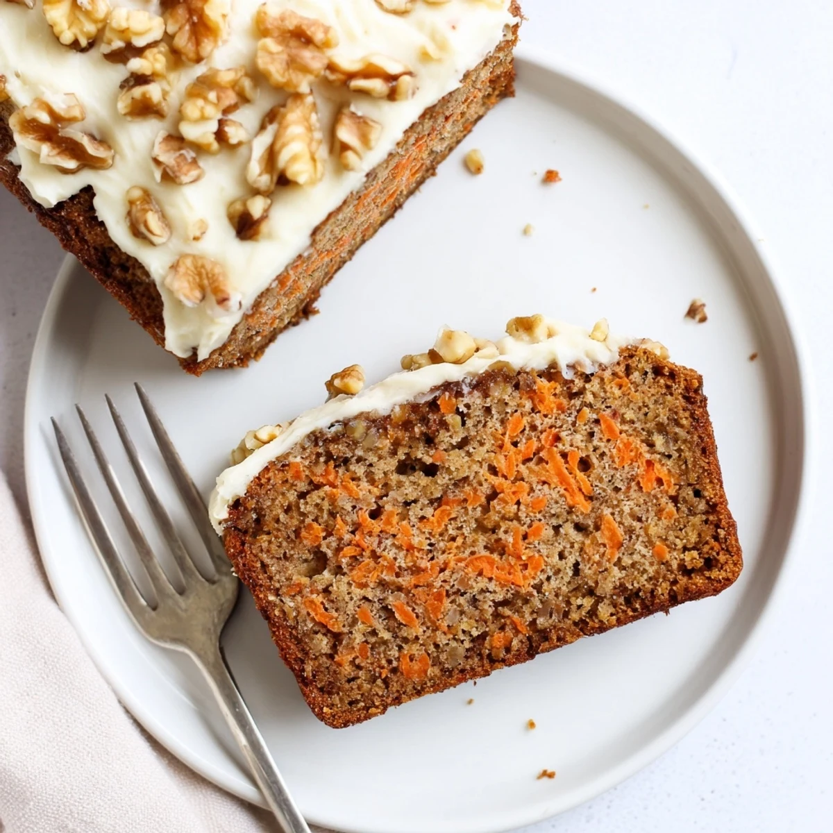 Golden brown carrot cake banana bread loaf dusted with powdered sugar on a wooden board