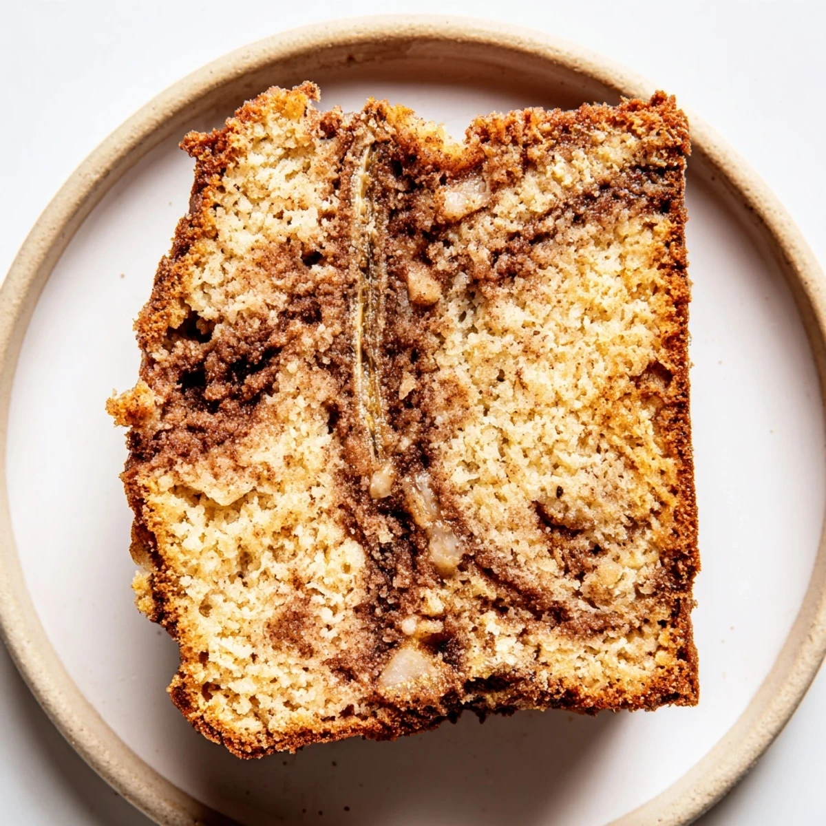Warm slice of Cinnamon Sugar Swirl Banana Bread topped with melting butter on rustic plate