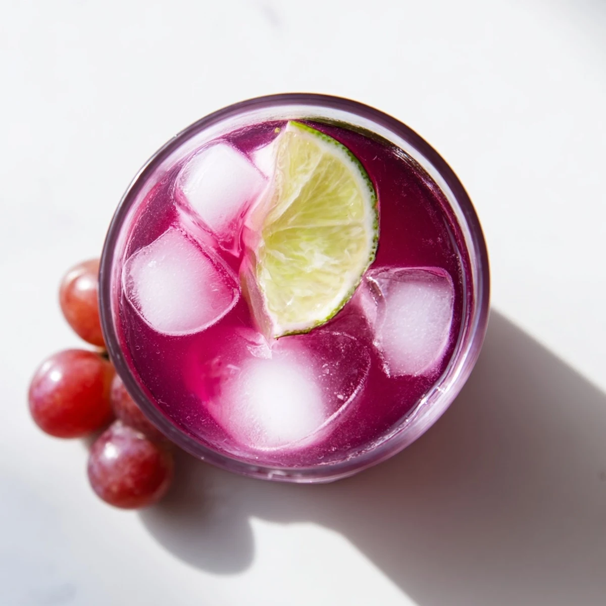 Pitcher of grape agua fresca poured over ice with fresh mint garnish