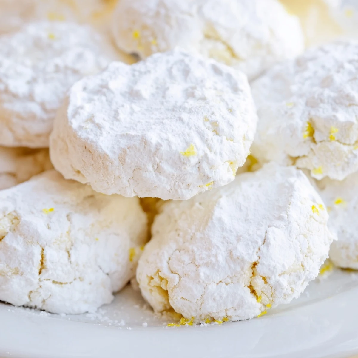 Powdered sugar coated Lemon Meltaways arranged on rustic wooden board with citrus wedges