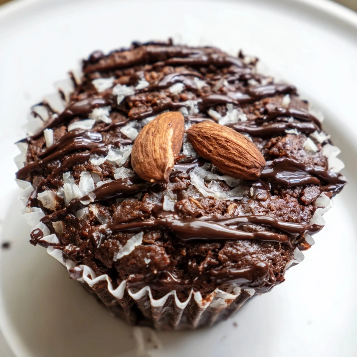 Rich flourless almond joy cupcakes topped with melted chocolate drizzle and roasted almonds