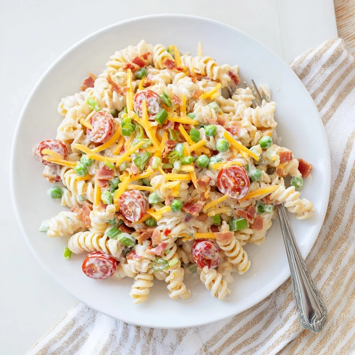 Colorful addictive crack pasta salad in a bowl topped with crunchy bacon bits and shredded cheddar