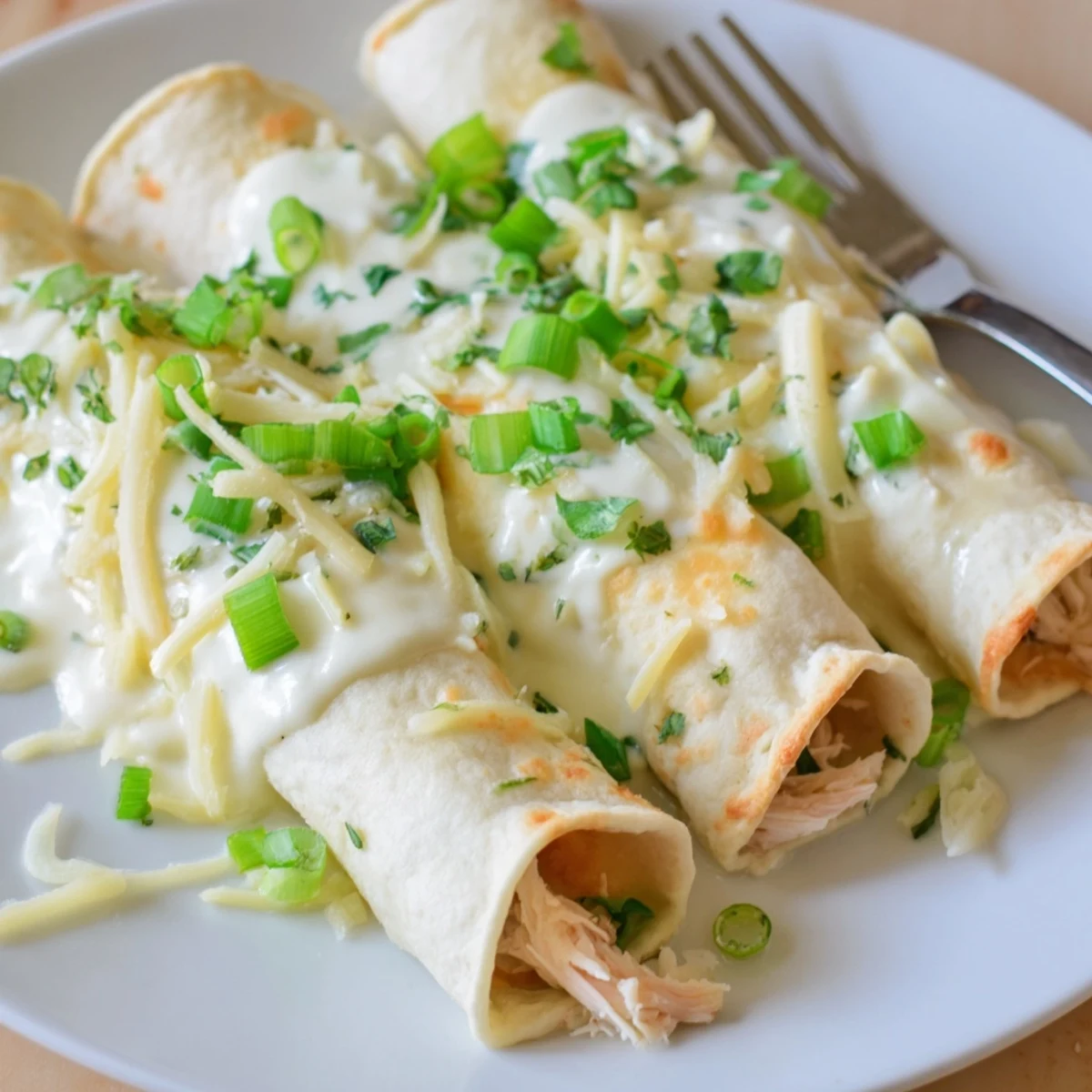 Creamy White Chicken Enchiladas bubbling with melted cheese, golden edges, garnished cilantro.