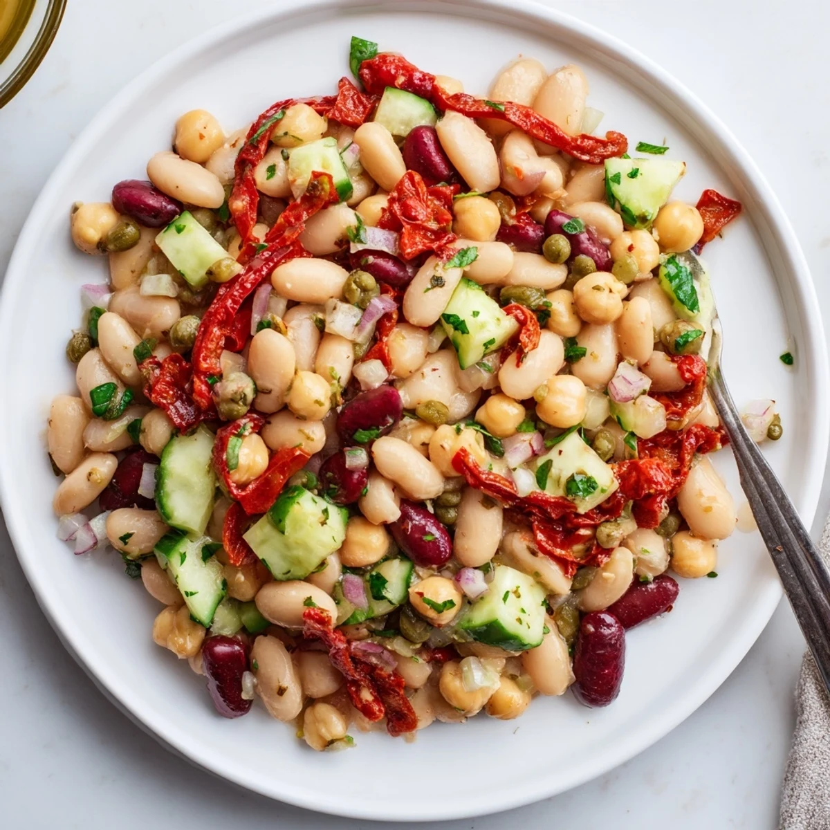 Dense Bean Salad With Sun Dried Tomatoes piled in bowl, vibrant tangy colors.
