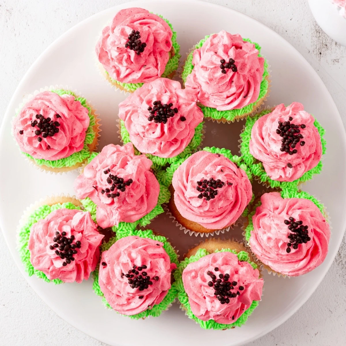 Watermelon cupcakes with creamy pink buttercream frosting and mini chocolate chips on wire rack