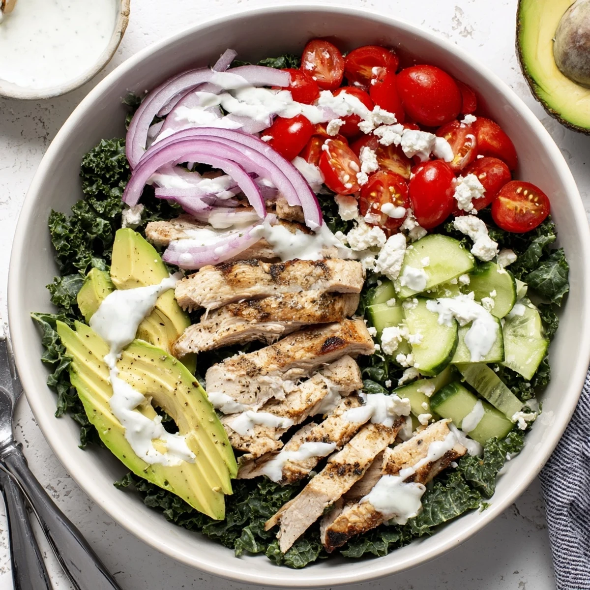 Golden sliced marinated chicken rests atop vibrant massaged kale with colorful fresh vegetables in a nourishing bowl