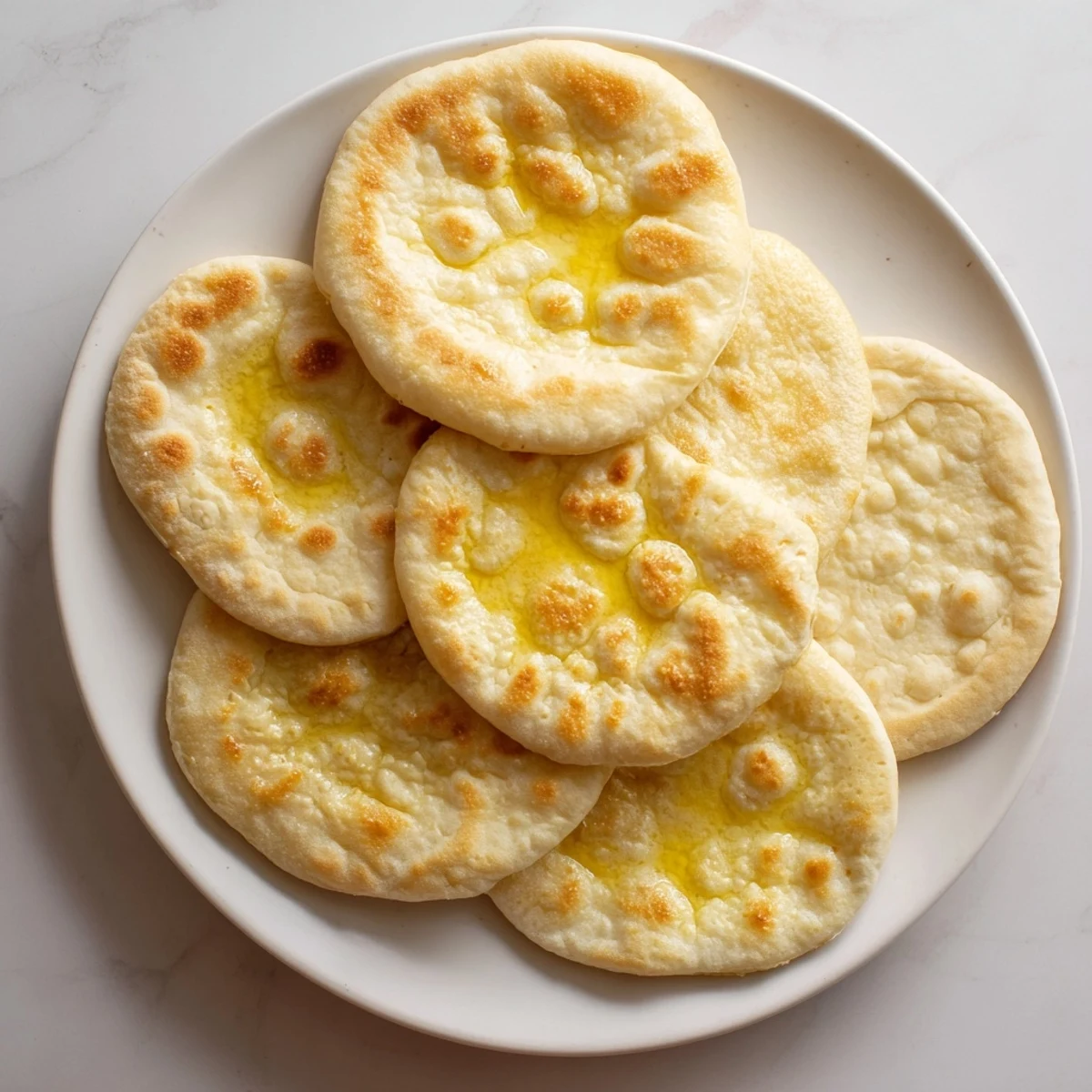 Warm homemade Turkish Bazlama bread stacked high on wooden serving board