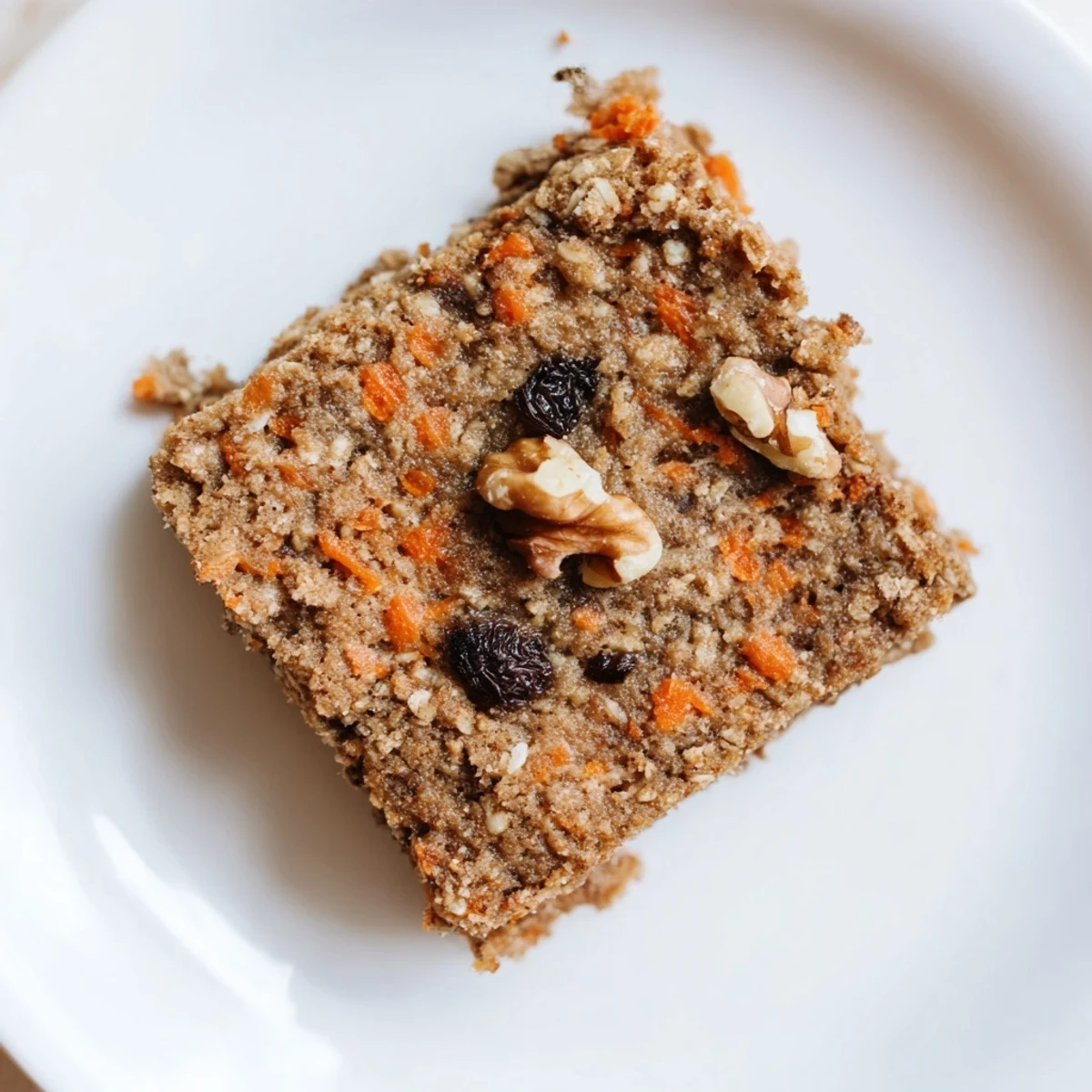 Wholesome flourless oatmeal carrot cake squares dusted with cinnamon and pecans on wooden board