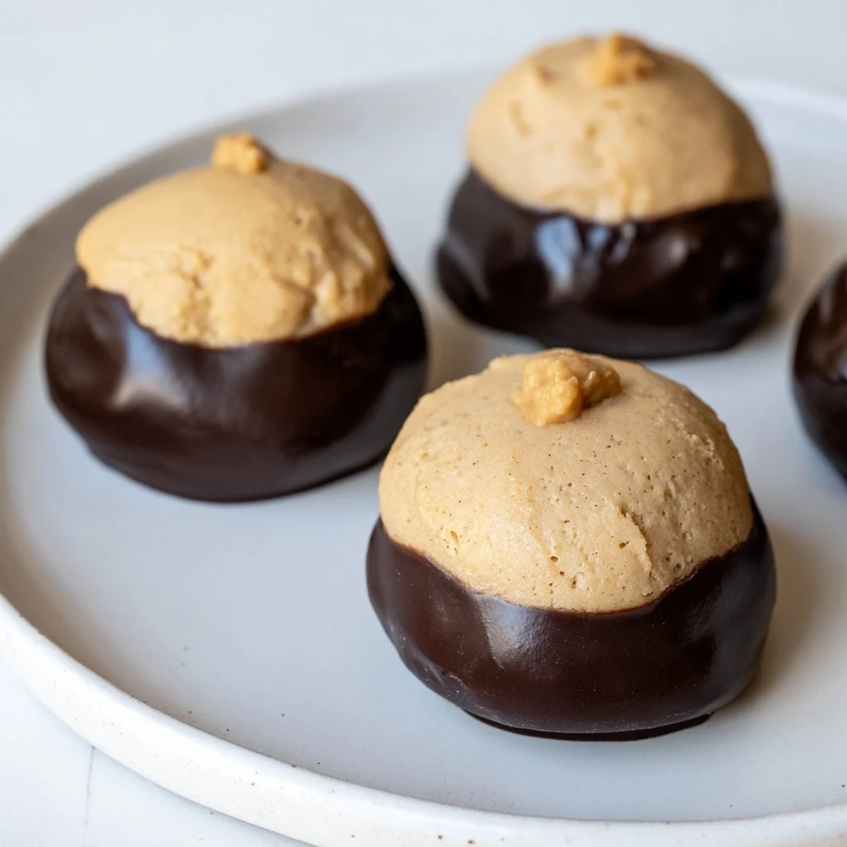Golden buckeye cookies with glossy chocolate bottoms on a rustic parchment-lined tray