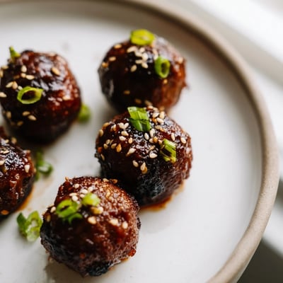 Crispy-edged Korean BBQ meatballs scattered with sesame seeds on a rustic platter
