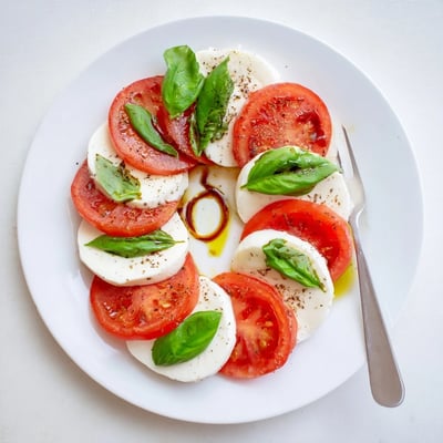 Bright Classic Caprese Salad drizzled with olive oil and balsamic glaze