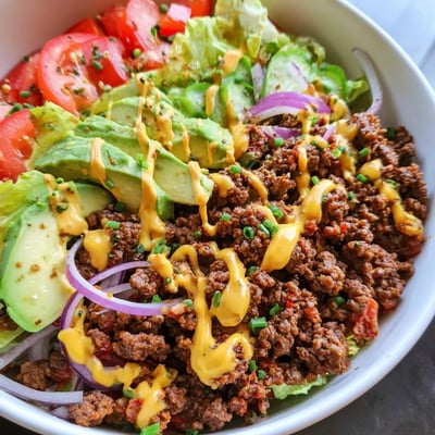Juicy ground beef burger bowls topped with ripe avocado, crisp lettuce, and tangy pickles